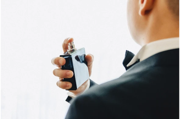 reunion-de-novios-detalles-chaqueta-zapatos-relojes-y-botones-el-dia-de-la-boda Hombre con traje aplicándose perfume